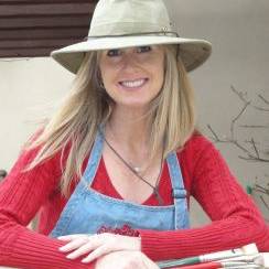 woman holding paint brushes wearing painting apron and hat